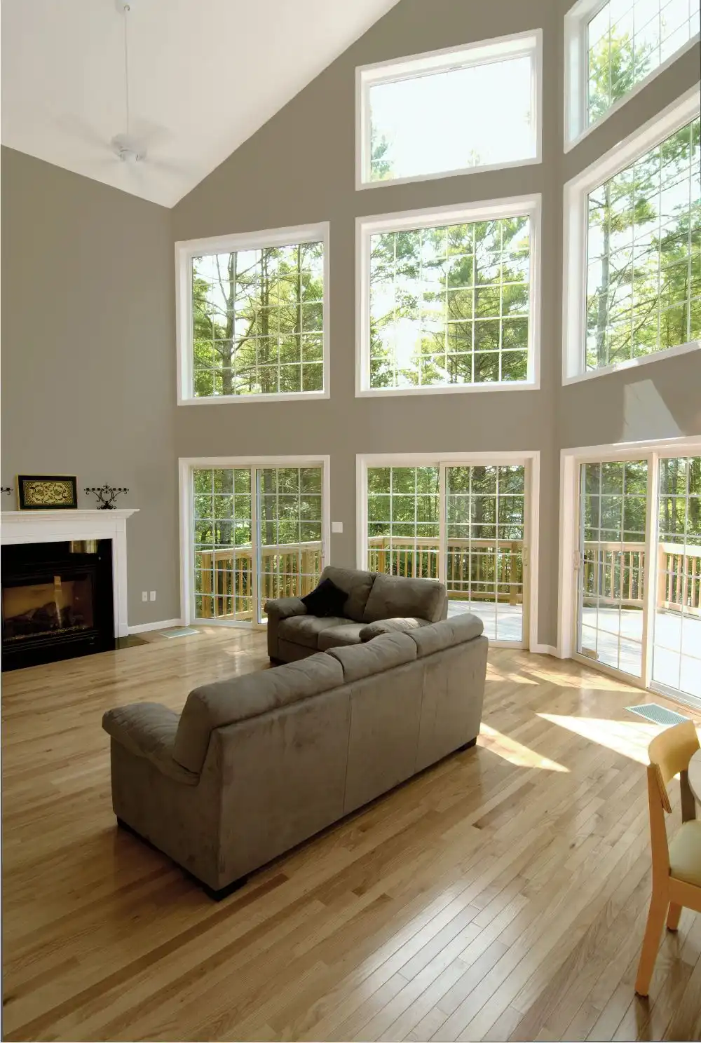 A gorgeous living room setting, with a high ceiling, sun filled windows and a sliding glass door